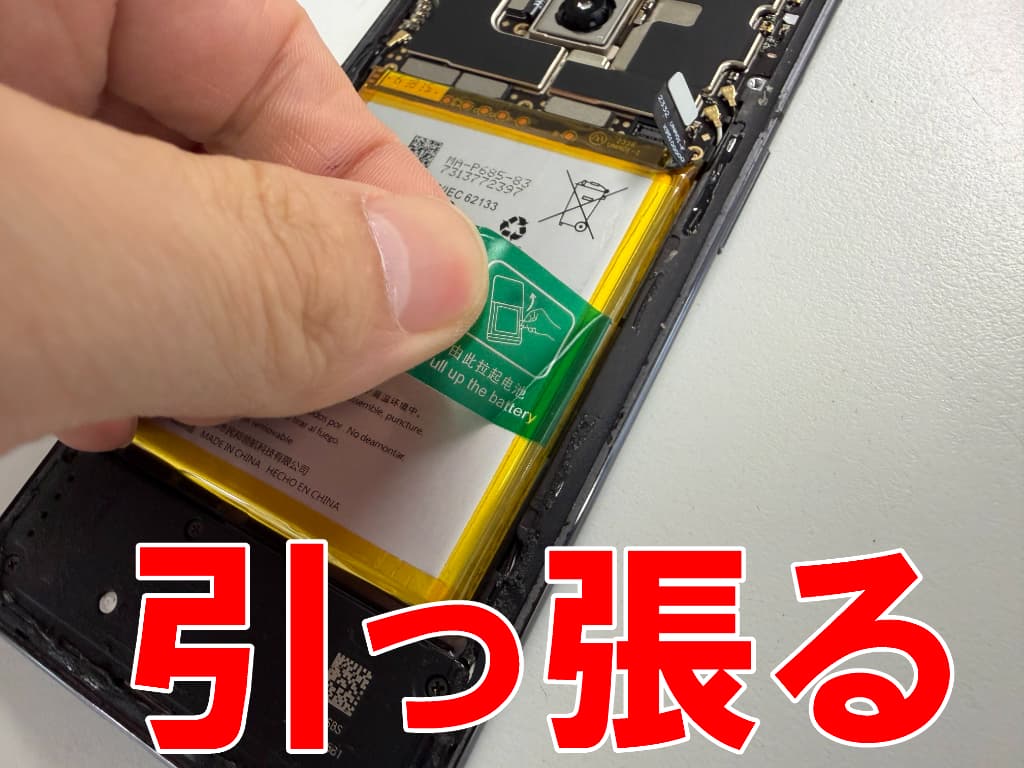 バッテリー固定シールを引っ張っている電池交換中のOnePlus7