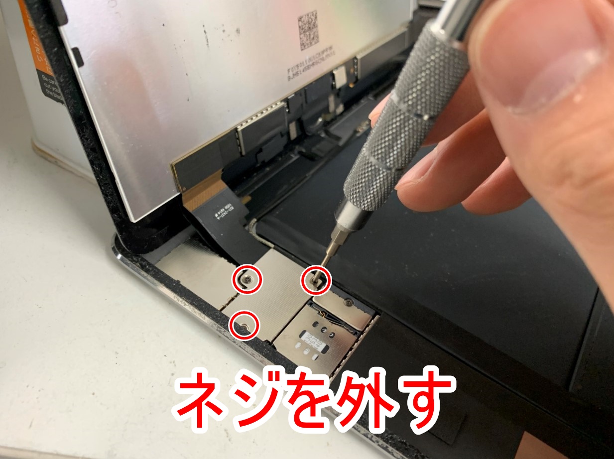 画面パーツのコネクタを止めた銀板のネジを外しているiPad Air2