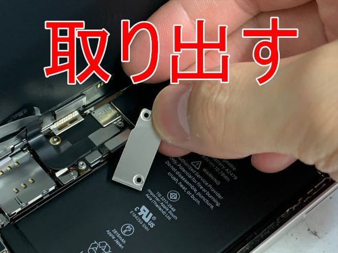 画面パーツとバッテリーコネクタを固定した銀板を取り出しているiPhone12