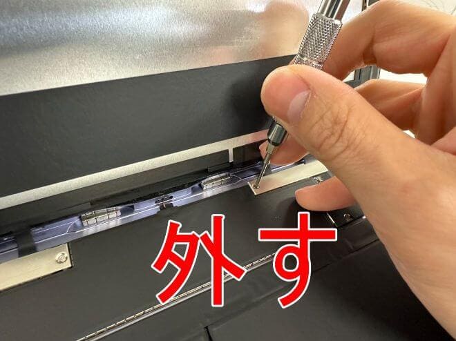 画面パーツを固定した銀板のプラスネジを外しているiPad Air(第5世代)