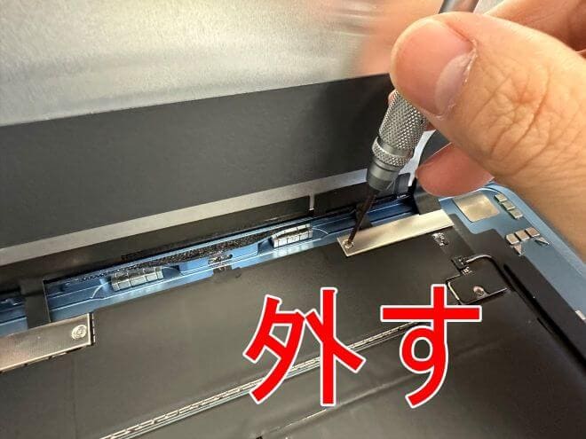 画面パーツコネクタを固定した銀板のネジを外しているiPadAir(第5世代)