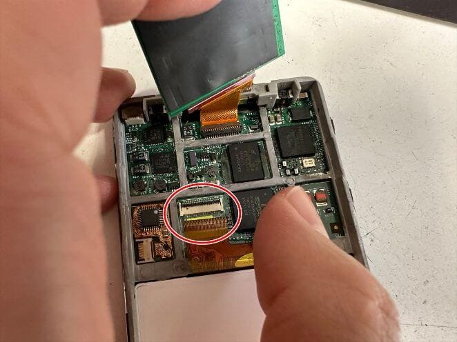 新品の液晶画面のコネクタを基板に接続しようとしているiPod classic