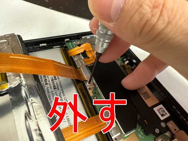 画面パーツとバッテリーコネクタを固定した銀板のネジを外しているLAVIE Tab PC-TE708KAS