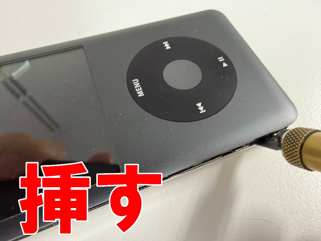 本体フレームと背面パネルの隙間にヘラを挿しているiPod classic