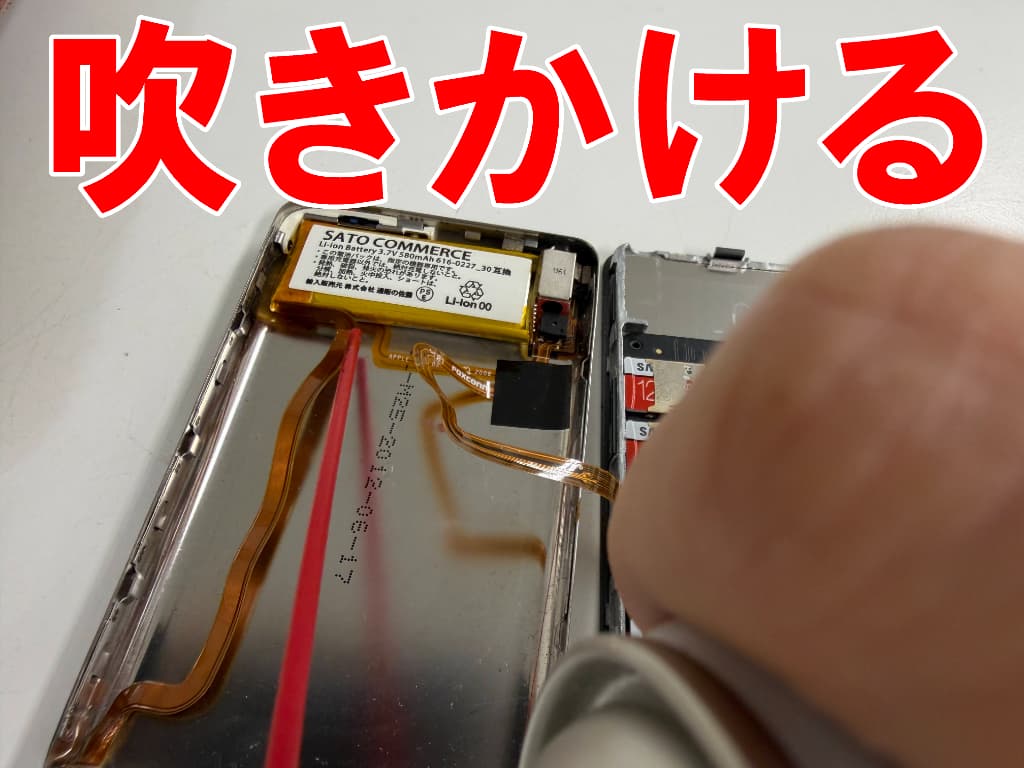 粘着面に粘着剥がしを吹きかけている電池パック交換修理中のiPod classic