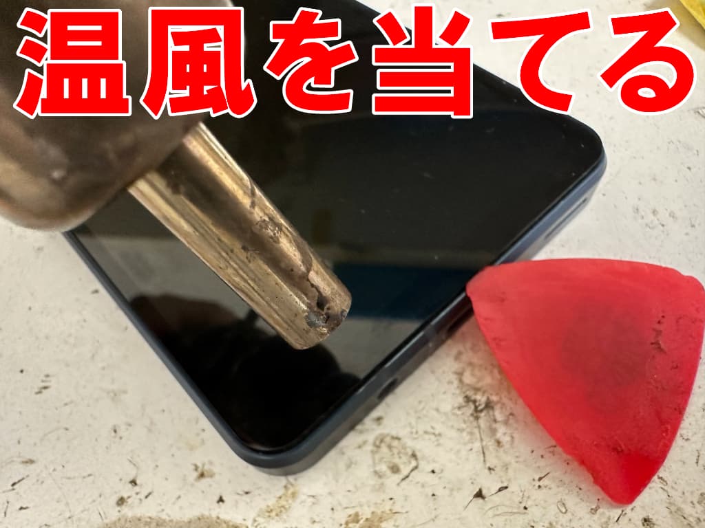 画面に温風を当てて粘着を弱めているAQUOS sense8