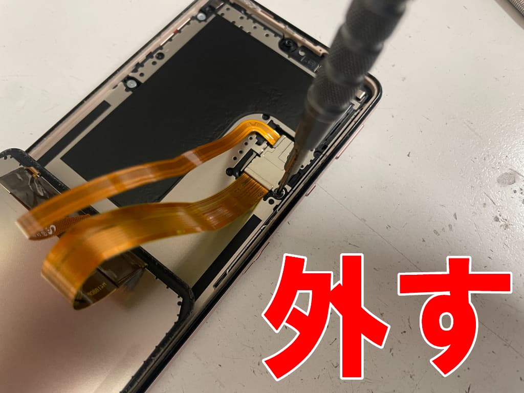 場面パーツコネクタを固定した銀板のネジを外している充電ポート修理中のAQUOSsense5G