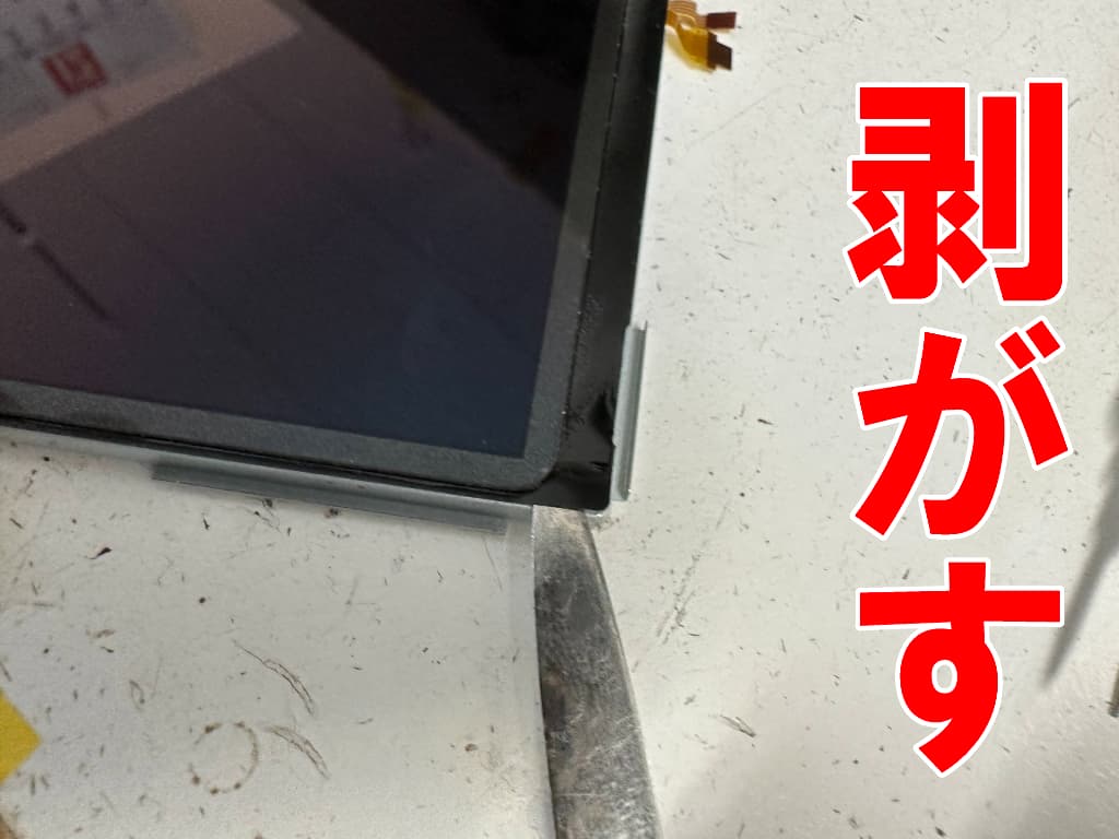 上液晶画面から表面アクリル部分を剥がしているNew3DSLL