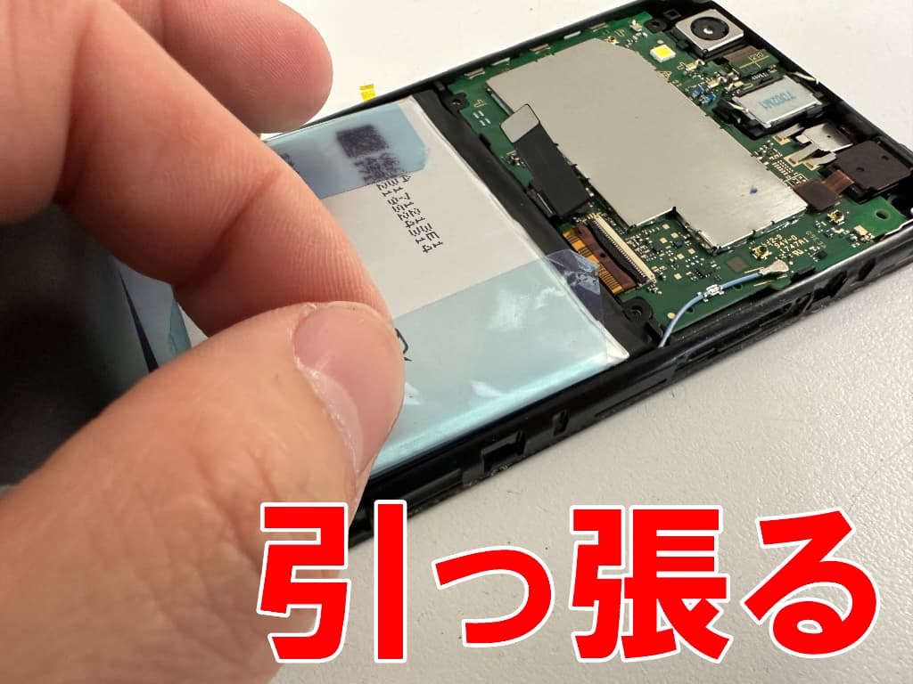 バッテリー固定シールを引っ張っているAndroid One S3