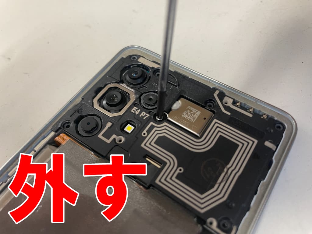 基板を覆ったプラスチックパーツを固定したネジを外しているドックコネクター修理中のGalaxy A53