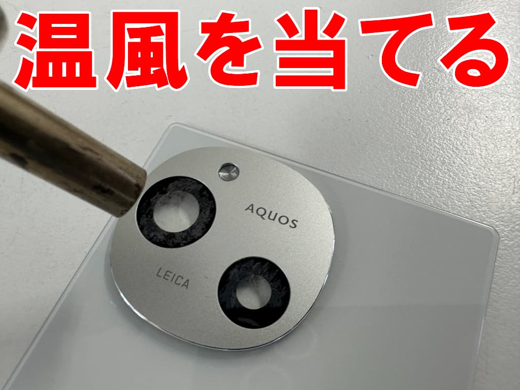 コーティングが剥がれたAQUOS R9の外カメラレンズに温風を当てている