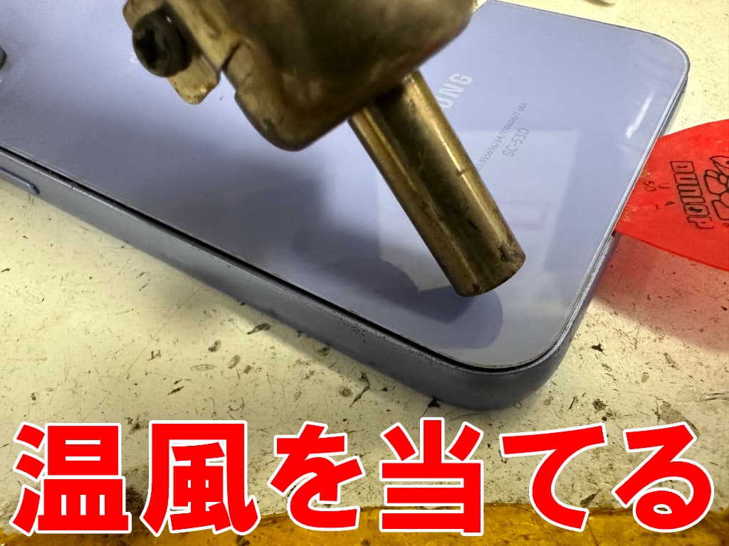 バックパネルに温風を当てているバッテリー交換修理中のGalaxyA54