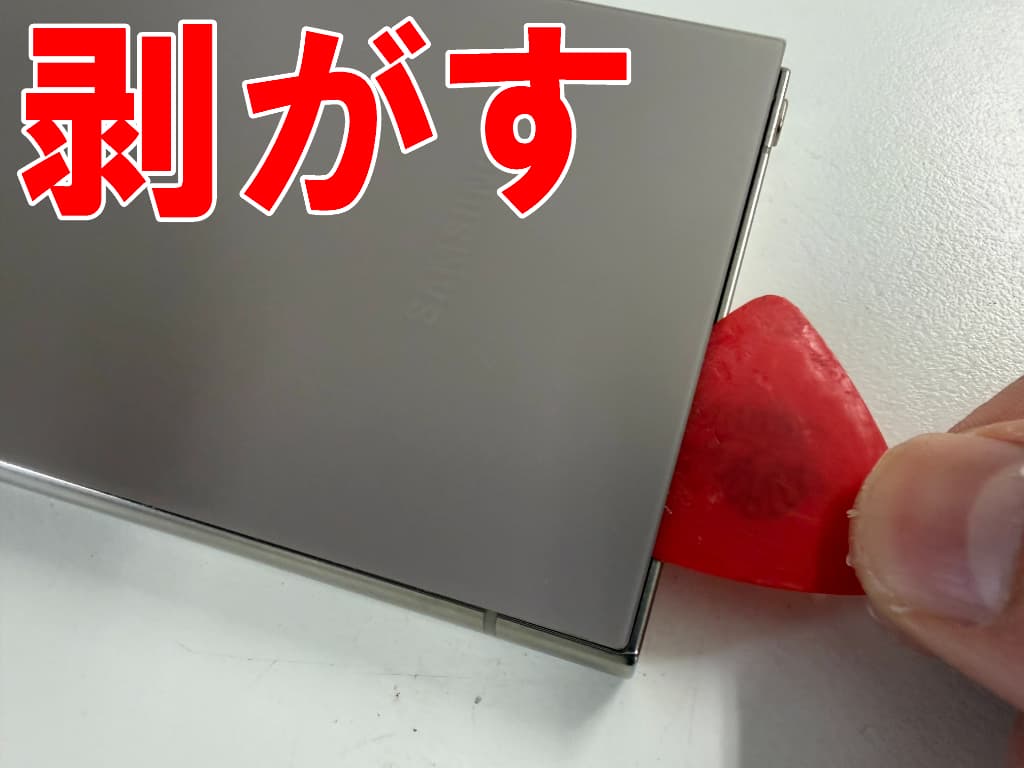 バックパネルの粘着を切っているパワーボタン修理中のGalaxyS24Ultra