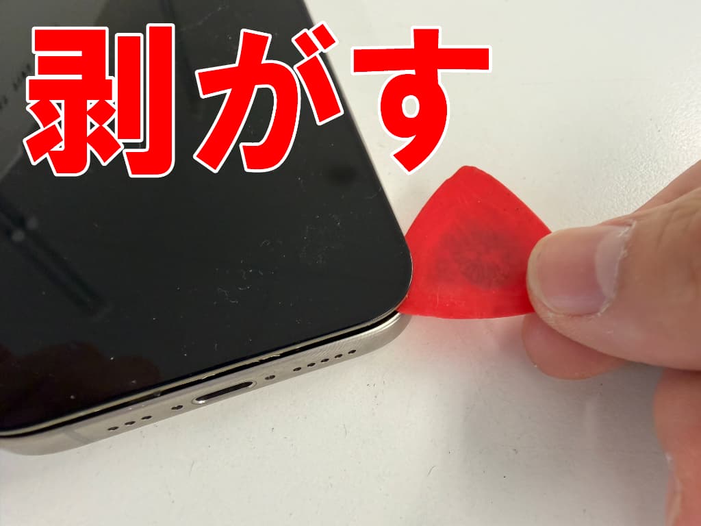フロントパネルと本体フレームとの粘着を切っている画面修理中のiPhone15Pro