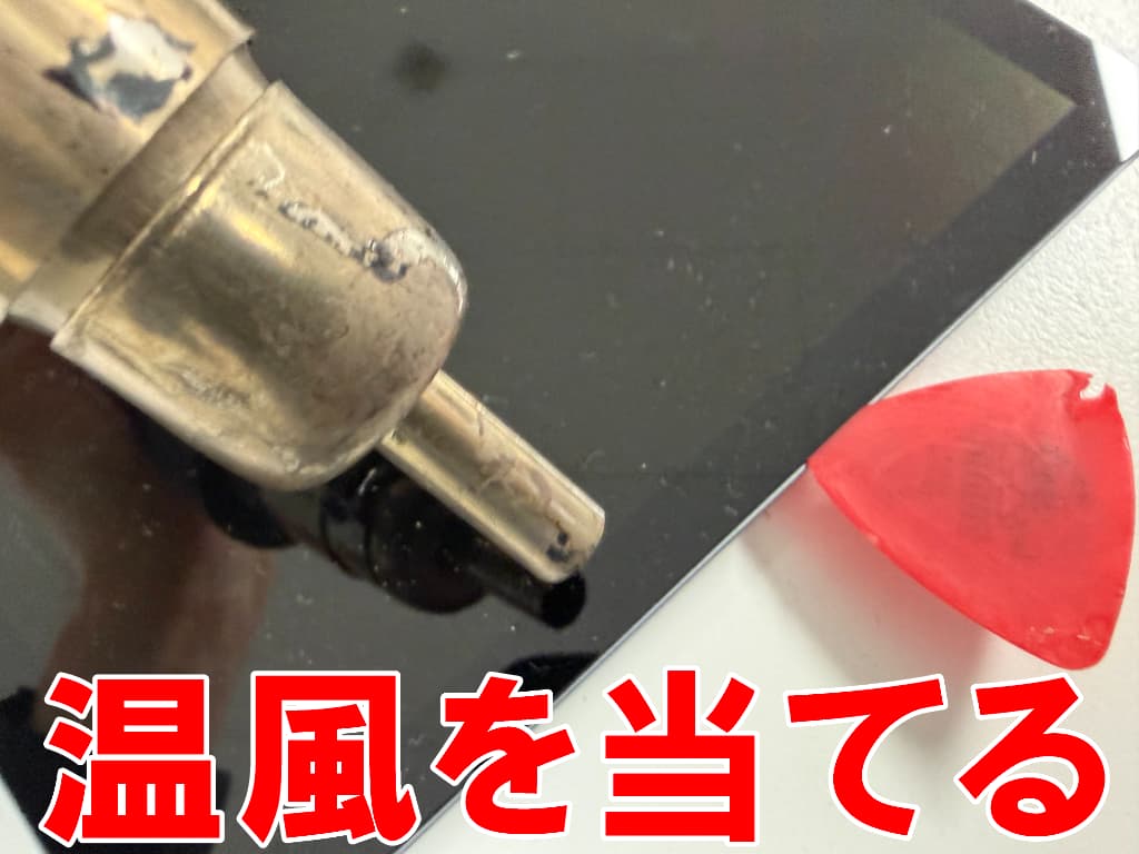 画面に温風を当てて粘着を弱めている充電器挿し込み口交換中のTB311FU