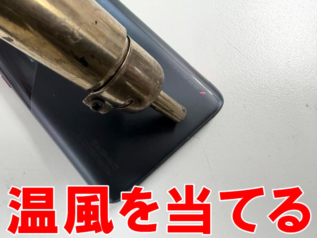 背面パネルに温風を当てている画面修理中のROG Phone7
