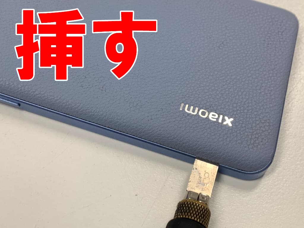 背面パネルにクラフトナイフを挿している画面修理中のXiaomi 13T