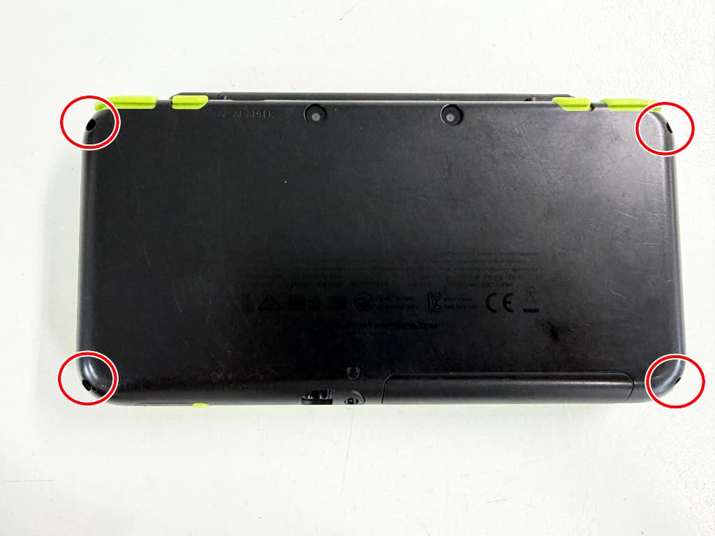 背面パネルの四つ角のネジを外しているパワーボタン修理中の2DS LL