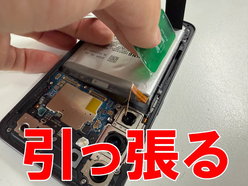 バッテリー固定シールを引っ張っているバッテリー交換中のGalaxy S24