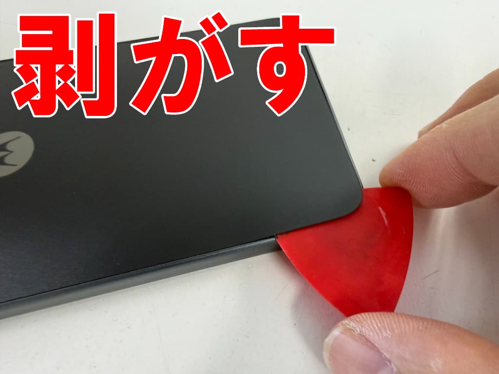 背面パネルと本体フレームとの粘着を剥がしているmoto g24