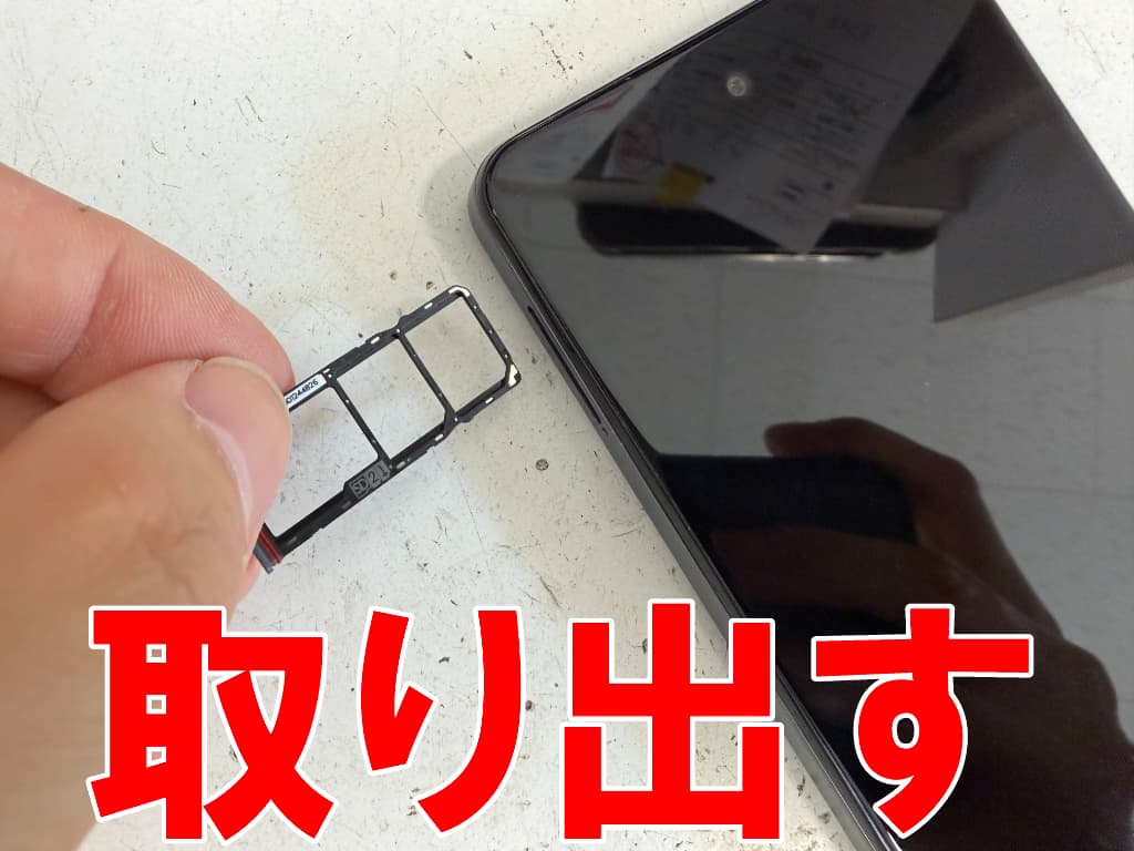 本体フレームからSIMトレイを取り出したバッテリー交換中のmoto g24