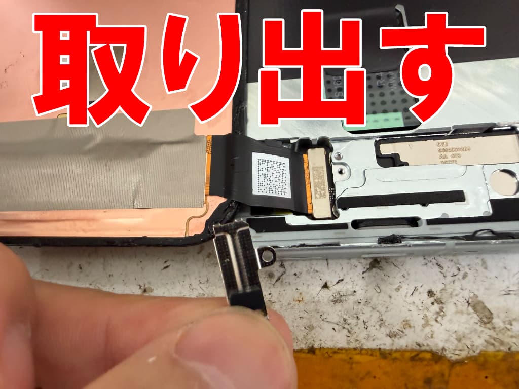 画面パーツコネクタを固定した銀板を本体フレームから取り出したピクセル10a