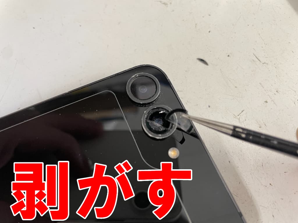 割れたリアカメラレンズを剥がしているGalaxy Z Flip6