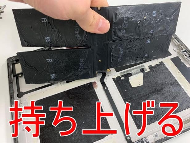 両側の粘着テープを剥がして持ち上げているSurface Pro5